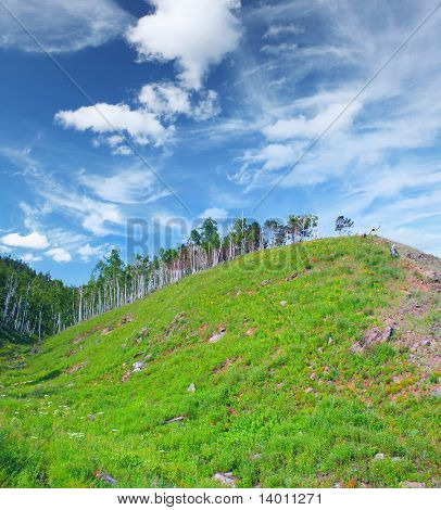 Enorme heuvel met groen gras en bomen op de top