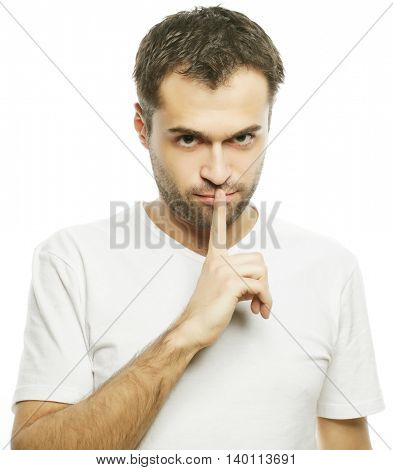 life style  and people concept: young man wearing white t-shirt making silence gesture, shhhhh!!