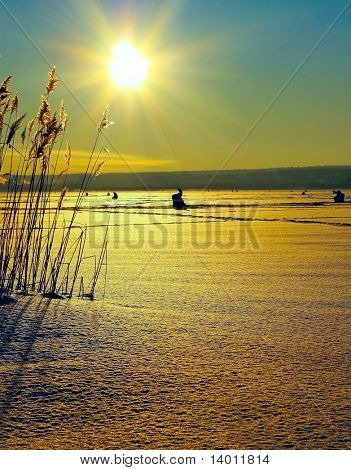 Winter fishermens on ice under sun