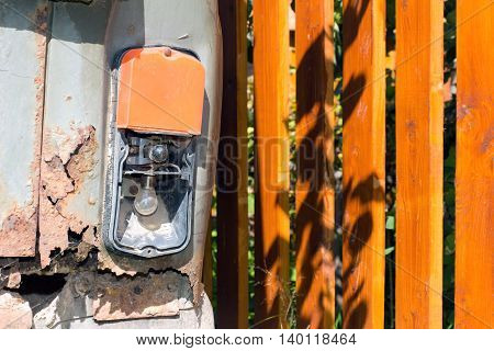 Old and rusty iron car. Broken tail lamp of the auto and the fence.