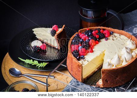 Cake with white chocolate mousse, lime confit, fruits and berries on top as decoration. The process of preparing a tea party with homemade fresh cake.