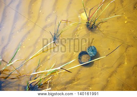 rusty tin can lying in the water. garbage in the water. the concept of water pollution, environmental damage