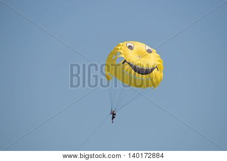 Man flying high on a colored parachute at sunrise