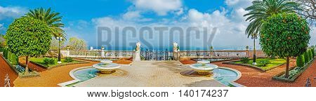 The scenic terrace in Bahai Gardens decorated with fountains and surrounded by palms and orange trees Haifa israel.