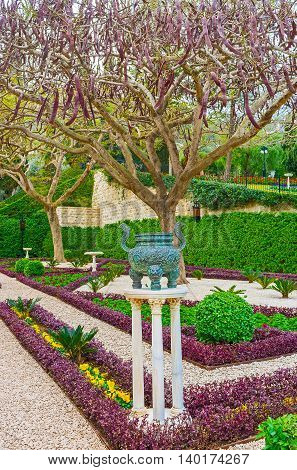 The Oriental vase on three slender pillars in the flower bed of Bahai Garden Haifa Israel.