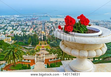 The stone vase with the bright red flowers decorates the handrail at the Bahai Garden viewpoint on the Carmel Mount top Haifa Israel.