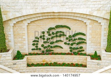 The decorative wall of Bahai Gardens with the flower beds and tiny trimmed trees Haifa Israel.