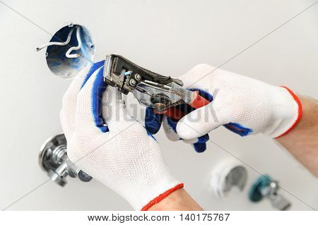 Electrican stripping insulation from wire for installation an electrical outlet.