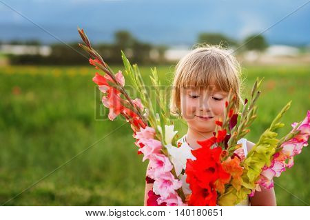 Beautiful bouquet of bright and colorful gladiolas flowers holding by cute little boy