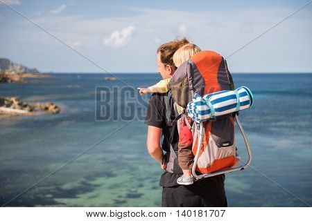 Father And Baby In Backpack Carrier Outdoors Near The Sea