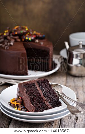 Slice of chocolate cake with glaze and ganache decorated with donuts