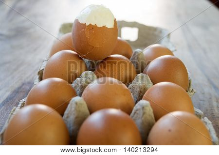 hardboiled egg partly shelled on a series of raw eggs