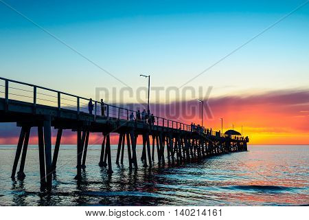 People relaxing on the Henley Beach Jetty at sunset South Australia. Color-toning effect applied