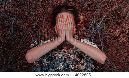 Pretty brunette woman covering her face with both hands