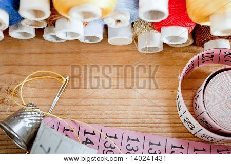 needle with thread and tape measure on the wooden desk