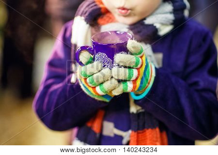 Little cute kid boy with cup of steaming hot chocolate or children punch. Happy child on Christmas market in Germany. Traditional leisure for families on xmas