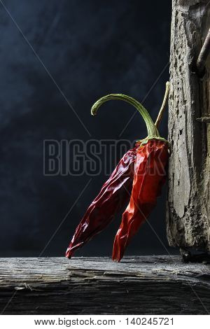 dried chili peppers on wood against a dark background