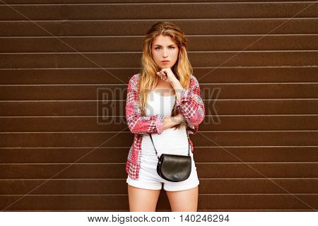 Portrait of young beautiful pensive blonde against a plain brown background.