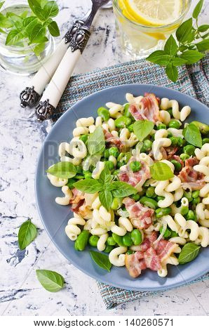 Pasta with bacon and vegetables in portion plate. Selective focus.