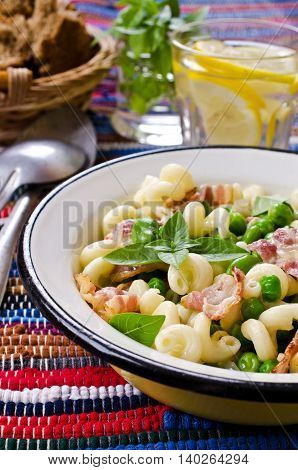 Pasta with bacon and vegetables in portion plate. Selective focus.