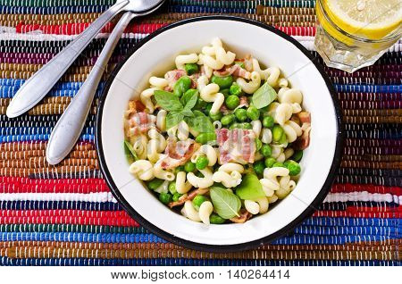 Pasta with bacon and vegetables in portion plate. Selective focus.