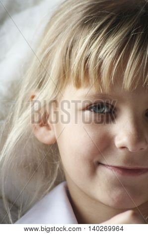 Smiling white girl portrait. Beautiful blonde hairs are streaming, the right blue eye and ear are visible