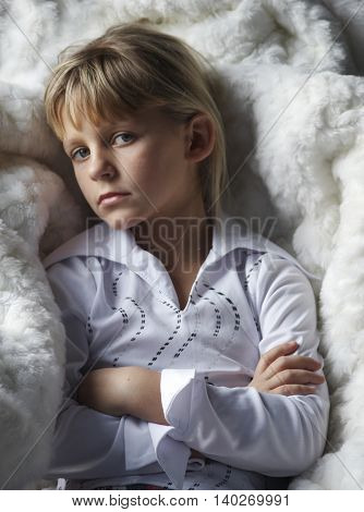 Girl sitting in white fur chair with serious eyes