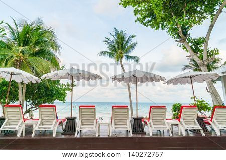 Beautiful beach chairs with umbrella around outdoor swimming pool neary sand and sea