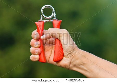 hand doing exercises with hand grip on green blurred background