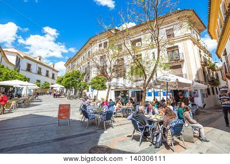 Cordoba, Andalusia, Spain - April 20, 2016: tourists while dining in restaurants of typical Barrio de la Juderia, famous for its narrow streets.
