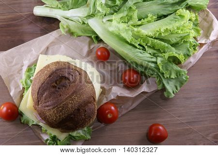 Picnic, sandwich with meat, cheese and fresh vegetables is lying on a rustic wooden table. Top view