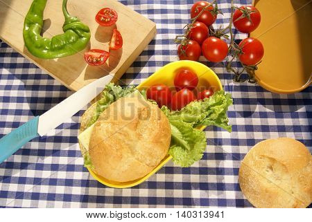 Cooking lunchbox. Yellow box lunch sandwich with cheese and a knife lying on a cutting board, fresh vegetables (pepper, tomatoes, lettuce)