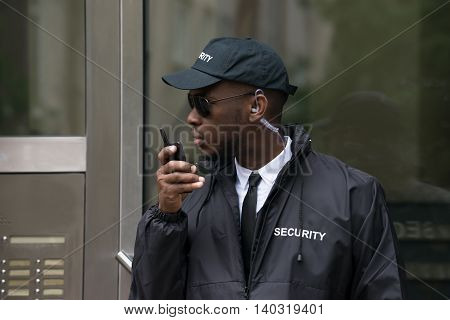 Portrait Of Young African Male Security Guard Talking On Walkie-Talkie