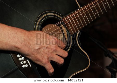 closeup of guitarist's hands strumming a guitar