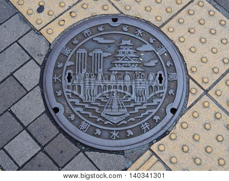 OSAKA, JAPAN - JUNE 08, 2016: A manhole cover in Osaka, Japan. A ship on Dotonbori canal and Osaka castle engraved on to a manhole cover as a symbol of an important city's landmark.