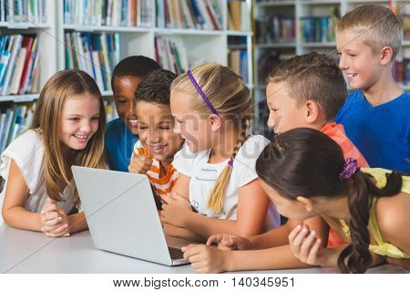 School kids using laptop in library at school