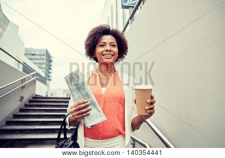 business and people concept - young smiling african american businesswoman with coffee cup going down stairs into city underpass