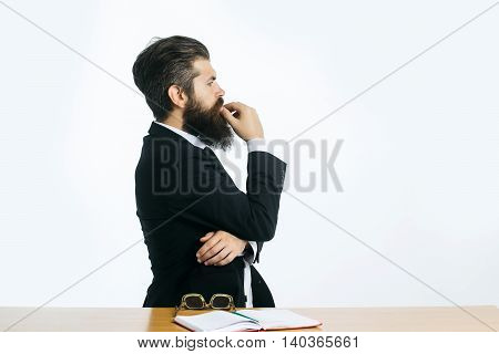 young handsome bearded man scientist or professor with long beard and teacher glasses with book or notepaper sitting at table isolated on white background