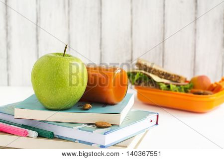School lunchbox: healthy food, fruits, books and apple over white table. Selective focus