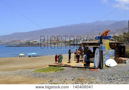 Playa De Las Americas beach Tenerife Canary Islands Spain Europe - June 18 2016: Surf shack with surfers and surf boards on the beach
