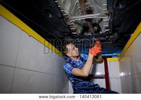 Auto mechanic working underneath a lifted car
