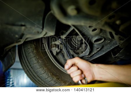 Auto mechanic working underneath a lifted car