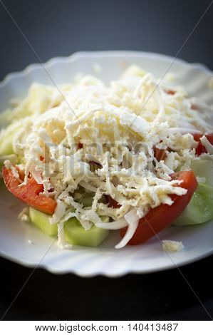 Traditional serbian salad on white plate on dark background.