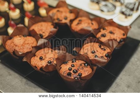 Freshly baked honey raisin muffins in rustic setting. Vintage pewter dishes with ingredients in background. Low key still life with directional natural lighting and shallow dof.