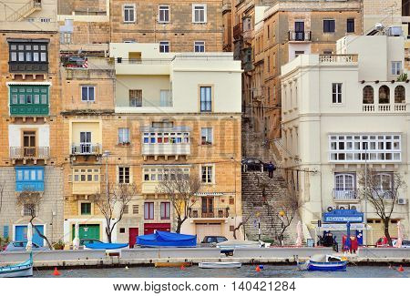 SENGLEA MALTA - MARCH 8: Traditional boats and cars on the waterfront of Senglea Isla on March 8 2013. Senglea is a small town in the Big Valletta city Malta.