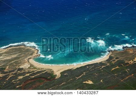Aerial of coastline of Molokai with waves crashing into Mo'omomi beach rocky shore and surrounding area of island with dirt roads largely undeveloped. April 2016.