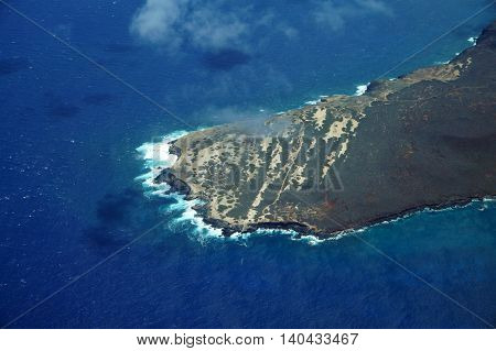 Aerial of Ilio Point on the Northwest coast of Molokai with waves crashing into shore and clouds in the air largely undeveloped. April 2016.