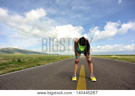 tired woman runner taking a rest after running hard on trail