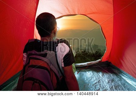camping man in tent and sun rising sky