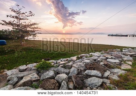 Sunrise by the shore with rock texture foreground
